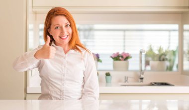 Kızıl saçlı kadın hareketi el ile mutlu yaşasın yapıyor mutfak at. Kameraya bakarak başarı gösteren ile ifade onaylama.