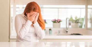 Mutfak yüz eller ile ağlayarak süre kapsayan üzgün ifade ile Kızıl saçlı kadın. Depresyon kavramı.