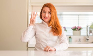 Kızıl saçlı kadına gösterilen ve parmakları ile işaret mutfak üçüncü ise kendinden emin ve mutlu gülümseyerek.