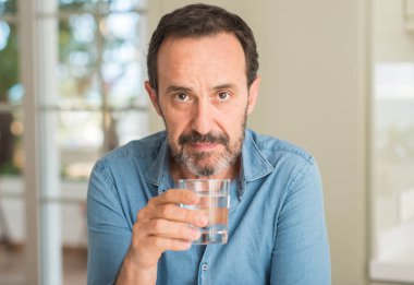 Orta yaş erkek ciddi düşünme akıllı yüzünde kendinden emin bir ifade ile su içme
