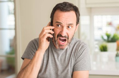 Bir sürpriz yüz, korkuyor ve heyecanlı korku ifadesi ile Smartphone şokta korktuğunu kullanan orta yaş adam