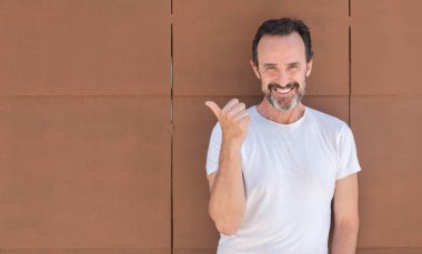 El ve parmak ile yukarı dönük mutlu yüz gülümseyen ile duvarın üzerinden ayakta yakışıklı komuta sizde