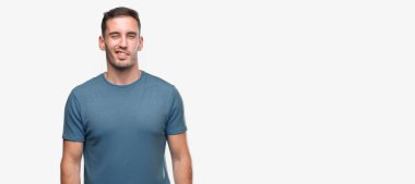 Yakışıklı genç casual adam seksi bir ifadeyle, neşeli ve mutlu yüzünü kameraya bakarak göz kırpıyor.