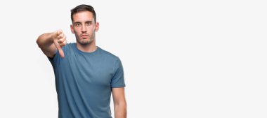 Mutsuz ve kızgın ret gösterilen ve başparmak aşağı hareketi ile negatif seyir yakışıklı genç casual adam. Kötü ifade.