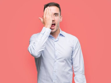 Yakışıklı genç işadamı yüz ve sürpriz duygu kendinden emin gülümseme ile el ile bir göz kapsayan.