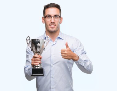 Ok işareti, başparmak ile parmak, mükemmel işareti yapıyor kocaman bir gülümseme ile kupa mutlu tutmak yakışıklı genç