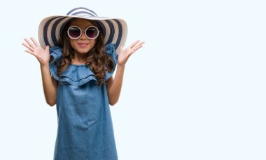 Güneş gözlüğü ve yaz şapka çok mutlu ve heyecanlı, kazanan ifade büyük gülümseme ile çığlık zaferini kutluyor ve ellerini kaldırdı esmer Latin kız