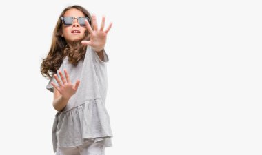 Şokta bağırarak korkuyor ve dehşet korku ifade dur hareketi el ile ile güneş gözlüğü takıyor esmer Latin kız. Panik kavramı.