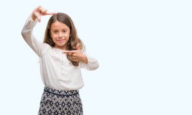 Elle yapma çerçeve ve parmakları ile mutlu yüz gülen esmer İspanyol kız. Yaratıcılık ve Fotoğrafçılık kavramı.