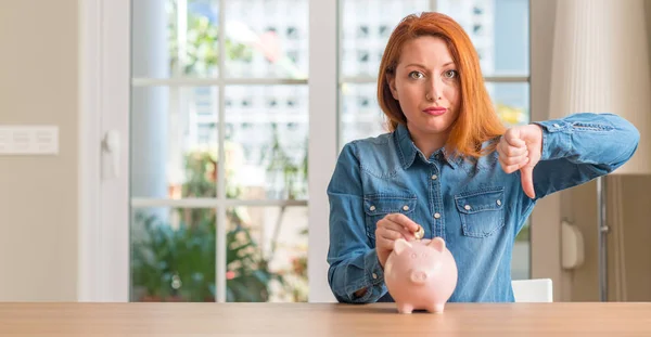 Roodharige Vrouw Bespaart Geld Piggy Bank Thuis Met Boos Gezicht — Stockfoto