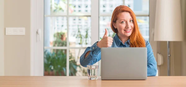 红发女子在家里用电脑笔记本电脑开心的笑着做 拇指竖起手指 好兆头 — 图库照片