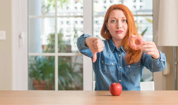 Rossa Donna Sceglie Tra Mela Ciambella Con Faccia Arrabbiata Segno — Foto Stock