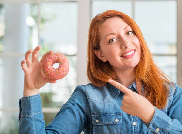Mulher Ruiva Segurando Donut Casa Muito Feliz Apontando Com Mão — Fotografia de Stock