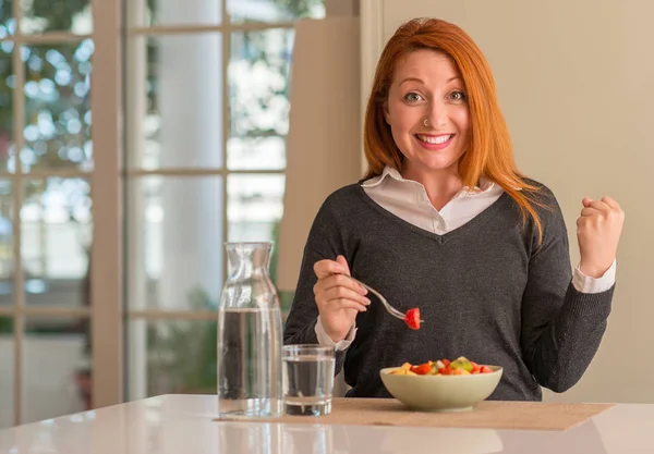 Meyve tabağı, kivi ve ev gurur çığlık ve kutluyor zafer ve başarı çok heyecanlı, çilek yeme Kızıl saçlı kadın duygu tezahürat