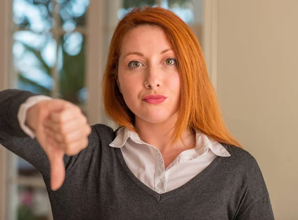 Kızıl saçlı kadın evde kızgın yüzü ile negatif antipati başparmak aşağı, ret kavramı ile gösterilen işareti