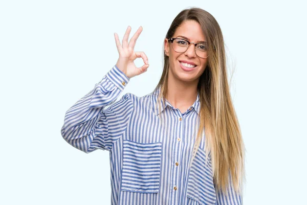 Şık gömlek ve gözlük el ve parmaklar ok işaretiyle yapıyor olumlu gülümseyen güzel ve genç birbayan. Başarılı ifade.