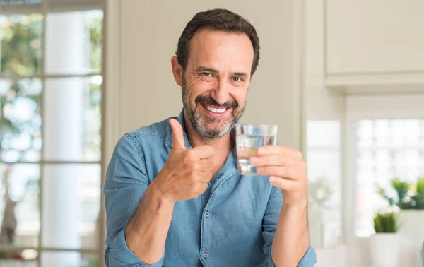 笑顔の サイン 優秀な兆候を親指をやって幸せな水のガラスを飲む中年男性 — ストック写真