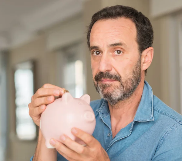 Mann Mittleren Alters Spart Geld Auf Sparschwein Mit Selbstbewusstem Gesichtsausdruck — Stockfoto