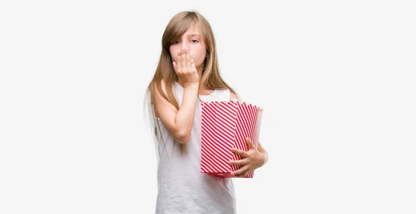 Young Blonde Toddler Holding Popcorn Pack Cover Mouth Hand Shocked — Stock Photo, Image
