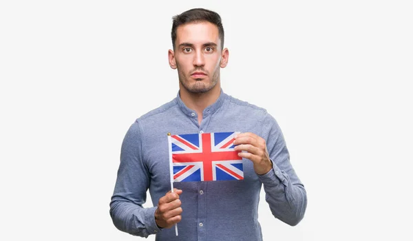 スマートの顔は深刻な思考に自信を持って式にイギリスの旗を保持しているハンサムな若い男 — ストック写真