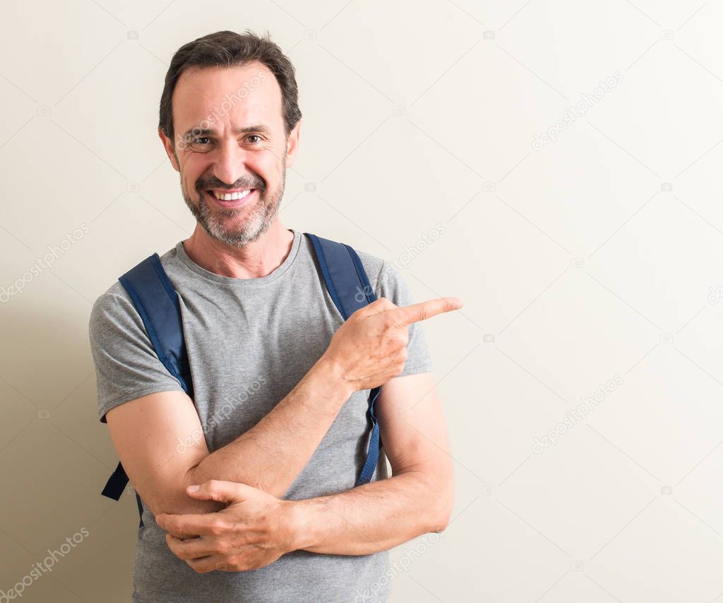 Senior man using backpack very happy pointing with hand and finger to the side