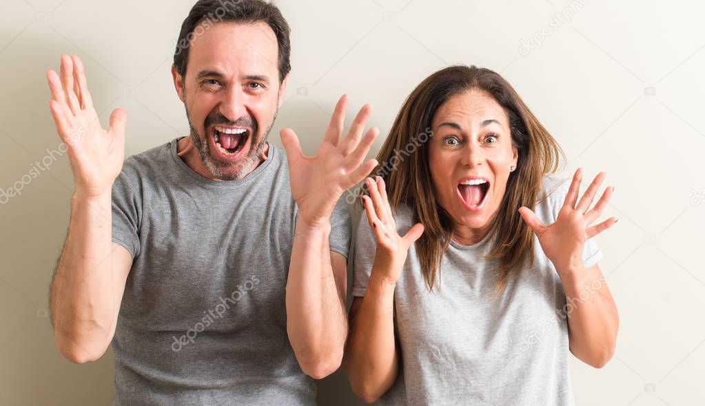 Middle age couple, woman and man very happy and excited, winner expression celebrating victory screaming with big smile and raised hands