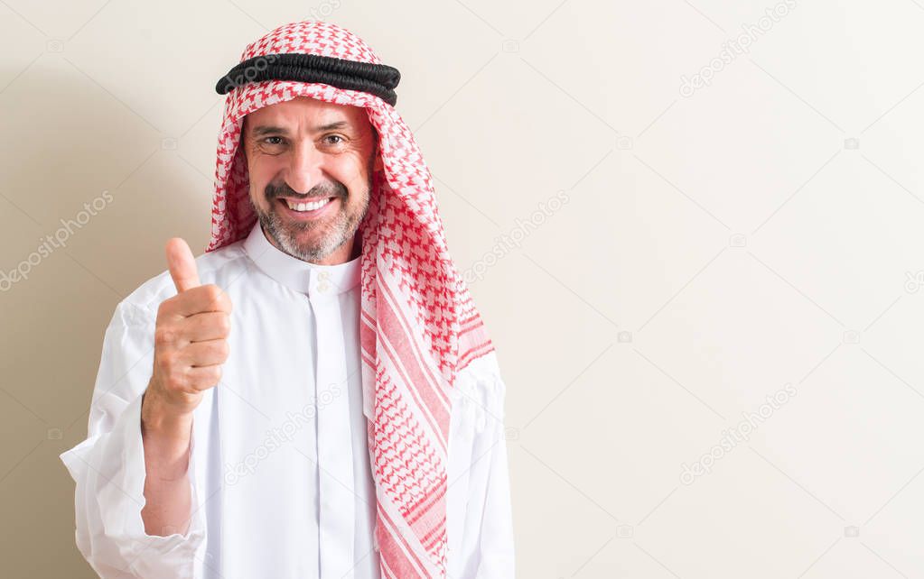 Senior arabic man happy with big smile doing ok sign, thumb up with fingers, excellent sign
