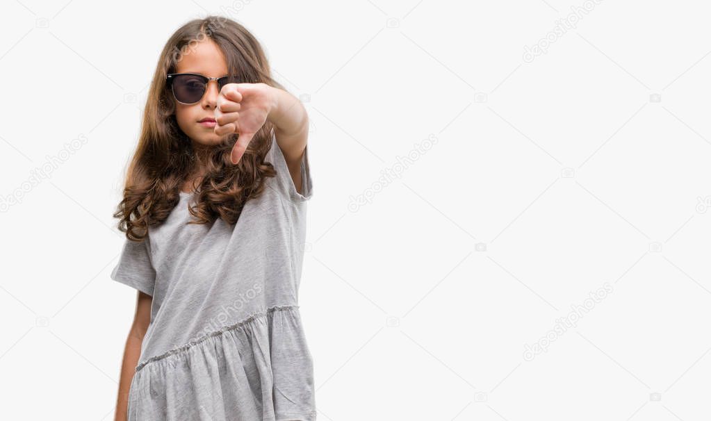 Brunette hispanic girl wearing sunglasses looking unhappy and angry showing rejection and negative with thumbs down gesture. Bad expression.