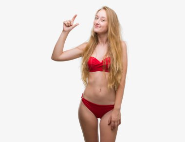 Kırmızı bikini gülümseyen ve boyutu işaret parmaklı ararken ve kamera işi el ile kendine güvenen el hareketi giymiş sarışın genç kadın. Ölçü kavramı.