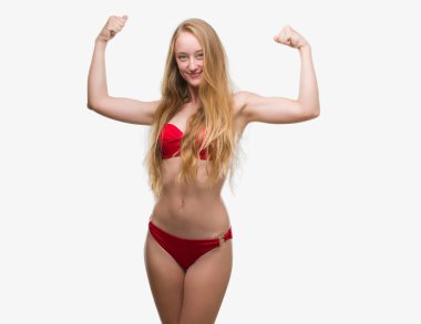 Kırmızı bikini gösteren giymiş sarışın genç kadın gururlu gülümseyen kas silah. Fitness kavramı.