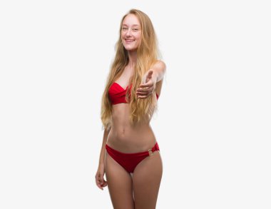 Tebrik ve konuksever dost sunan karşılıklı gülümseyen kırmızı bikini giyen sarışın genç kadın. Başarılı iş.