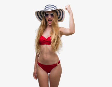 Bikini, güneş gözlüğü ve yaz şapka giymiş sarışın genç kadın rahatsız ve boşa çıkarmak ile öfke, çılgın da yükseltilmiş el ile bağırmaya kavramı öfke