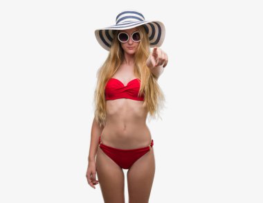 Sarışın genç kadın giyen bikini, güneş gözlüğü ve kamera ve size parmak ile işaret yaz şapka, el işareti, pozitif ve kendinden emin bir jest ön