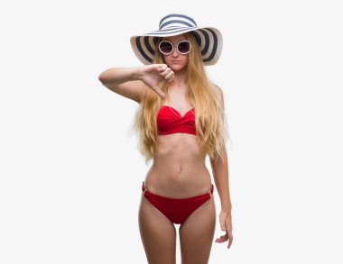 Bikini, güneş gözlüğü ve kızgın yüzü, eksi işareti aşağı antipati başparmak ile gösterilen, ret kavramı ile yaz şapka giymiş sarışın genç kadın