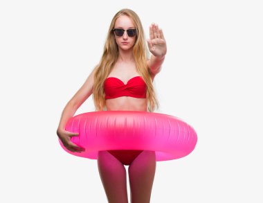 Bikini ve holding pembe flatör açık eliyle dur işareti ile ciddi ve kendine güvenen ifade, savunma jest yapıyor giymiş sarışın genç kadın