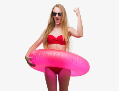 Bikini ve pembe flatör rahatsız tutarak ve öfke, çılgın ve yükseltilmiş el, öfke kavramı ile diye bağıran ile sinirli bağırarak giymiş sarışın genç kadın