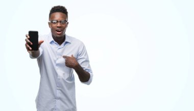 Kendisi için sürpriz yüz işaret parmağı ile akıllı telefon kullanan genç Afro-Amerikan adam