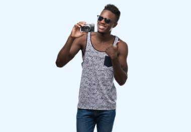 Vintage fotoğraf makinesi ok işareti, başparmak ile parmak, mükemmel işareti yapıyor kocaman bir gülümseme ile mutlu tutan genç Afro-Amerikan adam