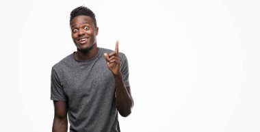 Gri t-shirt işaret parmağı ile başarılı fikir giyen genç Afro-Amerikan adam. Çıktıktan ve mutlu. Bir numara.
