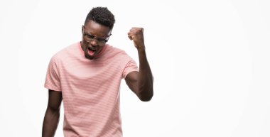 Öfkeli ve sinirli sinirli ve öfke ile bağırarak süre öfkeli yumruk yükselterek pembe t-shirt giyen genç Afro-Amerikan adam. Öfke ve agresif kavramı.