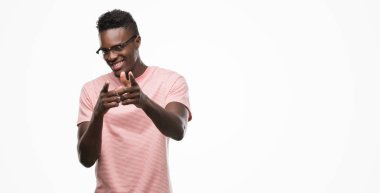 Fotoğraf makinesi ile mutlu ve komik yüzü pembe tişört işaret parmak giyen genç Afro-Amerikan adam. İyi enerji ve vibes.