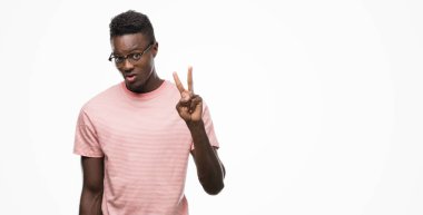 Gösterilen ve parmakları ile işaret pembe t-shirt giyen genç Afro-Amerikan adam ikincisi ise kendinden emin ve mutlu gülümseyerek.