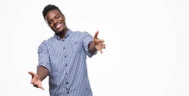 Sarılmak için kollarını açarak gülümseyerek kameraya bakarak mavi gömlek giymiş genç Afro-Amerikan adam. Neşeli ifade kucaklayan mutluluk.