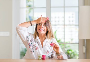 Genç kadın evde kafasına, utanç ile şok el ve yüz, öfkeli ve sinirli sürpriz ile vurguladı macarons yeme. Korku ve hata için üzgün.