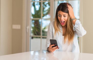 Smartphone sürpriz tutan genç kadın. Panik ve şok duygu evde