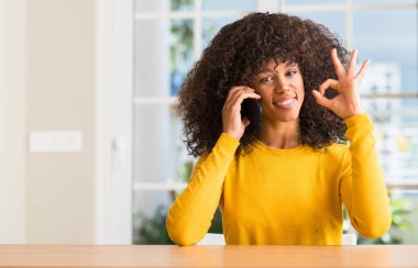 Afrikalı-Amerikalı kadın parmakları, mükemmel sembolü olan ok işareti yapıyor smartphone kullanarak