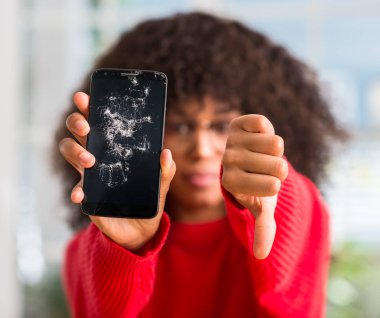 Kızgın yüz, eksi işareti aşağı antipati başparmak ile gösterilen, ret kavramı ile kırık smartphone tutan Afrikalı-Amerikalı kadın