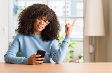 El ve parmak ile tarafına işaret çok mutlu Smartphone kullanarak güzel bir Afrikalı-Amerikalı kadın