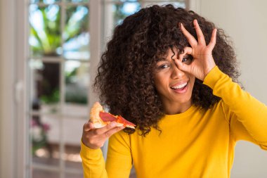 Afrikalı-Amerikalı kadın mutlu yüz el parmaklarının arasından seyir göz üzerinde ok işaretiyle yapıyor gülümseyen pepperoni pizza dilimi yemek hazır