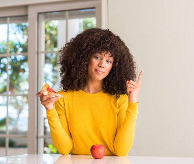 Afrikalı-Amerikalı kadın elma ve pizza arasında seçim yapma dilim çok mutlu el ve parmak ile işaret yan